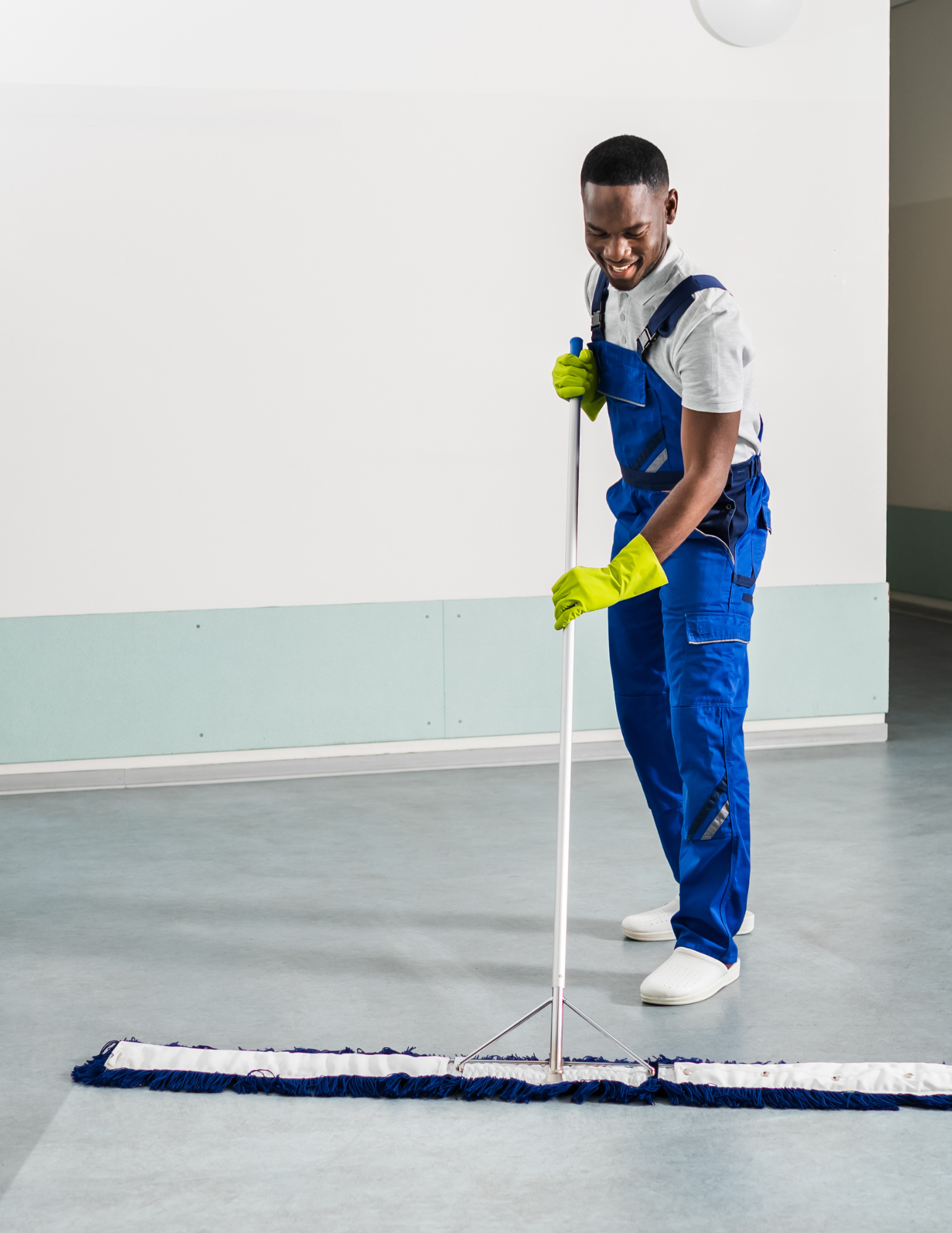 Uniformed cleaner dust-mopping a large office floor